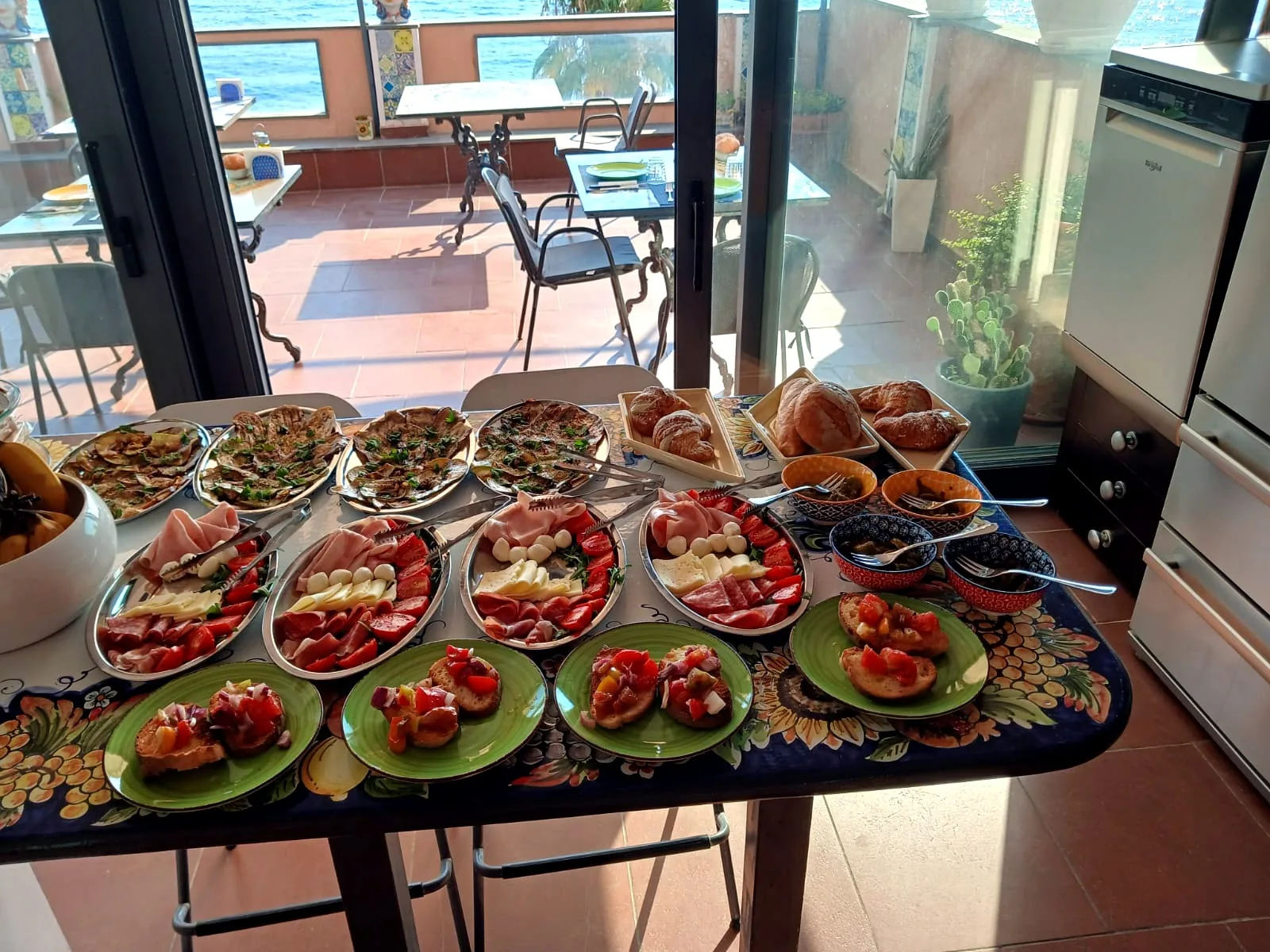 La tavola della colazione con cornetti, salumi, formaggi, verdure e bruschette davanti alla terrazza